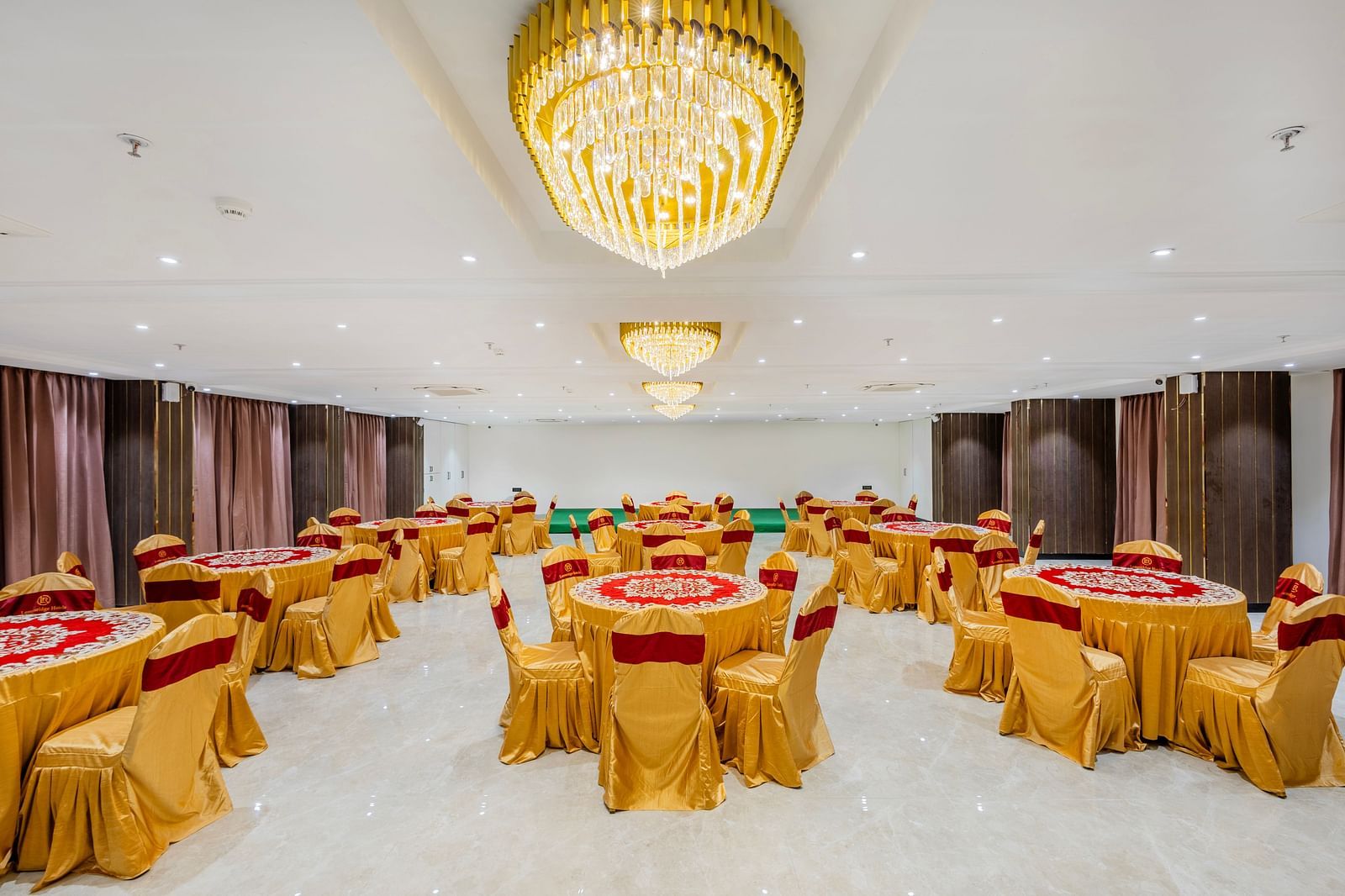 Lemonridge Hotels, KPHB | Banquet hall with round dining tables and chairs, featuring a unique ceiling light.